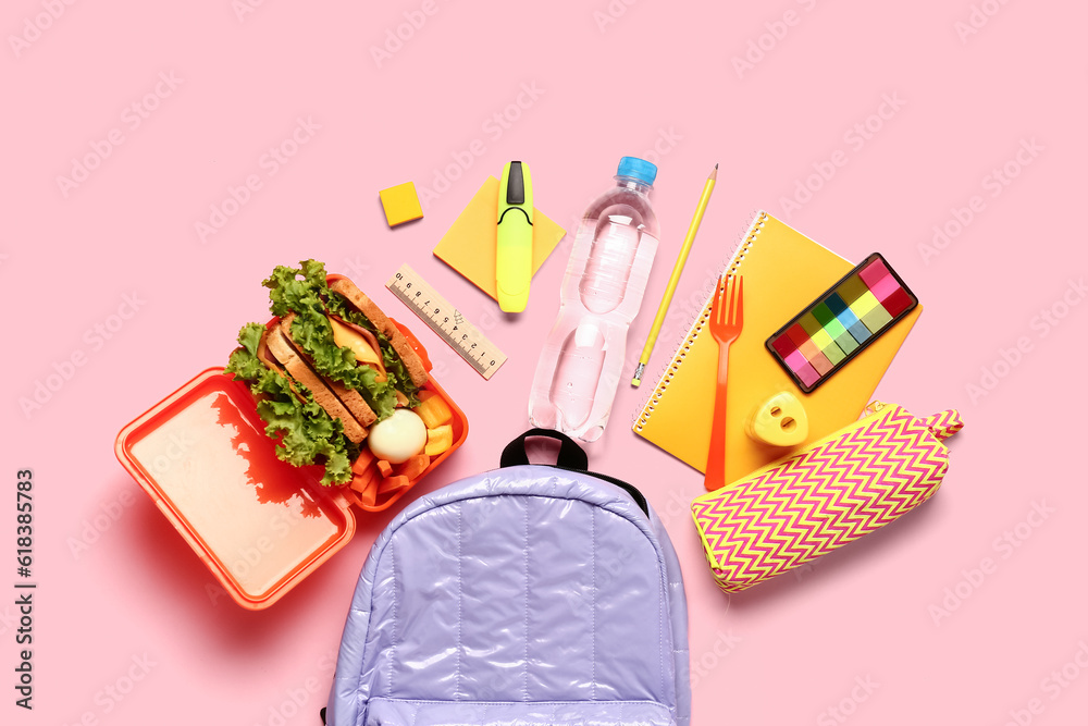Backpack, stationery, bottle of water and lunchbox with tasty food on pink background