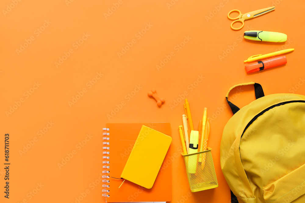 School backpack with different stationery on orange background