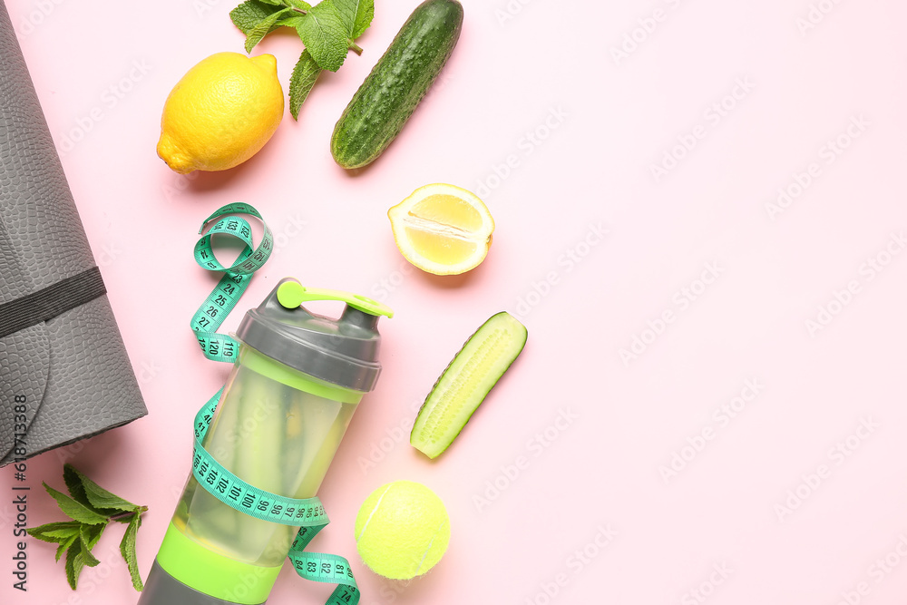 Bottle of lemonade with cucumber and sport equipment on pink background