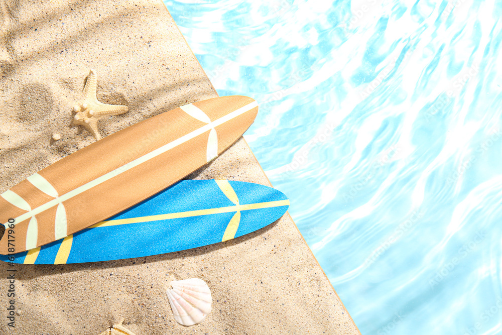 Mini surfboards with starfish and seashell on sand near water