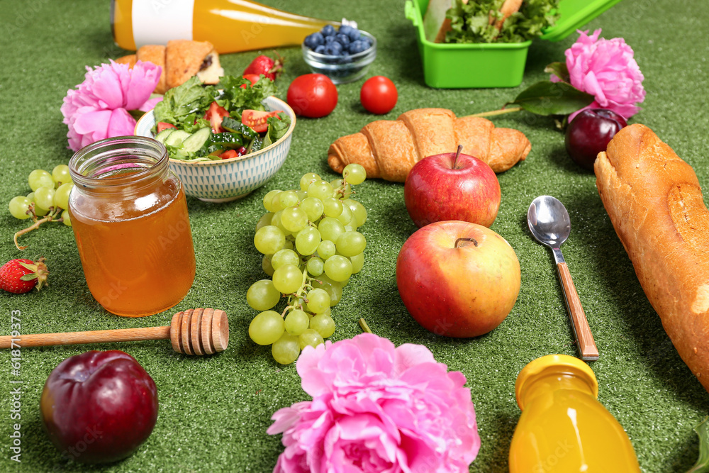 Composition with different tasty food for picnic, juice and peony flowers on green background, close
