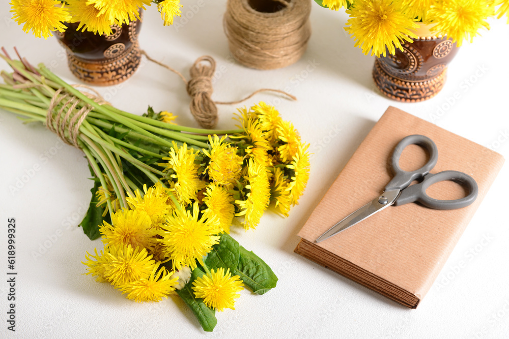 Yellow dandelion flowers, rope, scissors and book on light table
