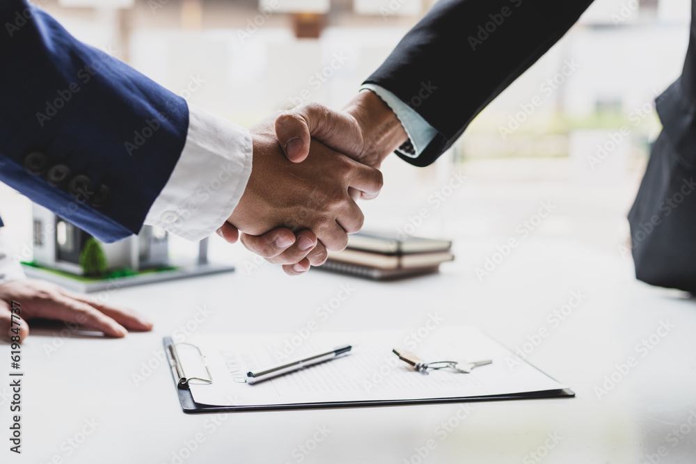 Businessman and real estate agent shaking hands after negotiating home purchase agreement.