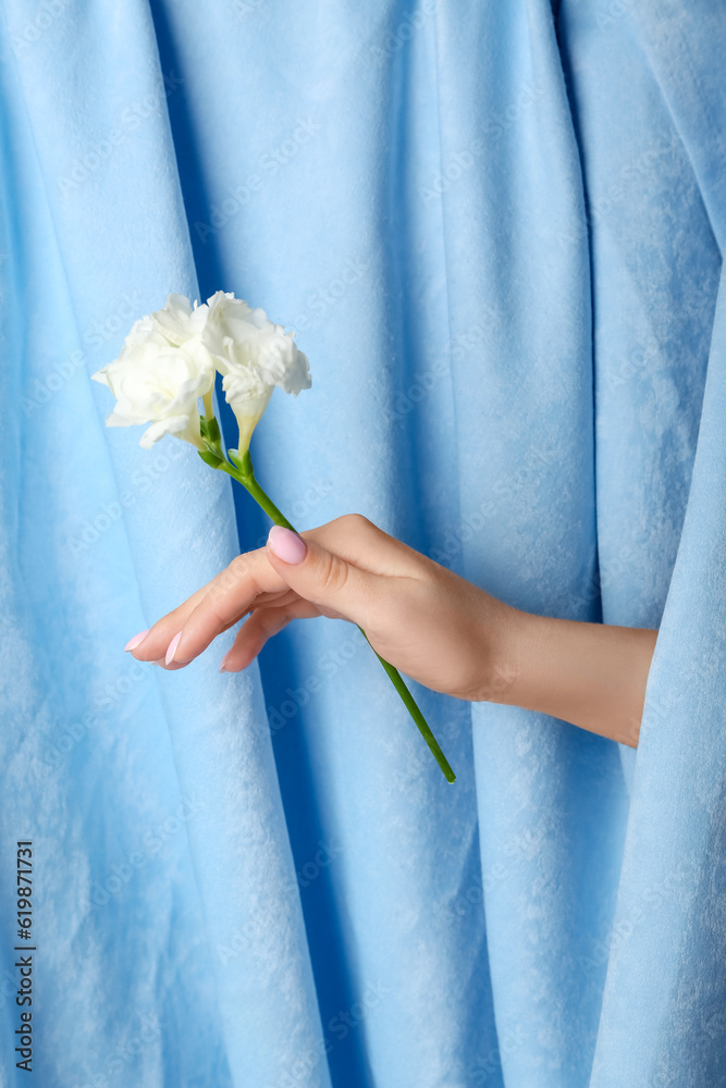Woman with white flowers against blue fabric background. Hand care concept
