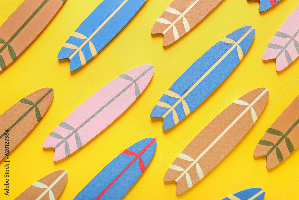 Many different colorful mini surfboards on yellow background