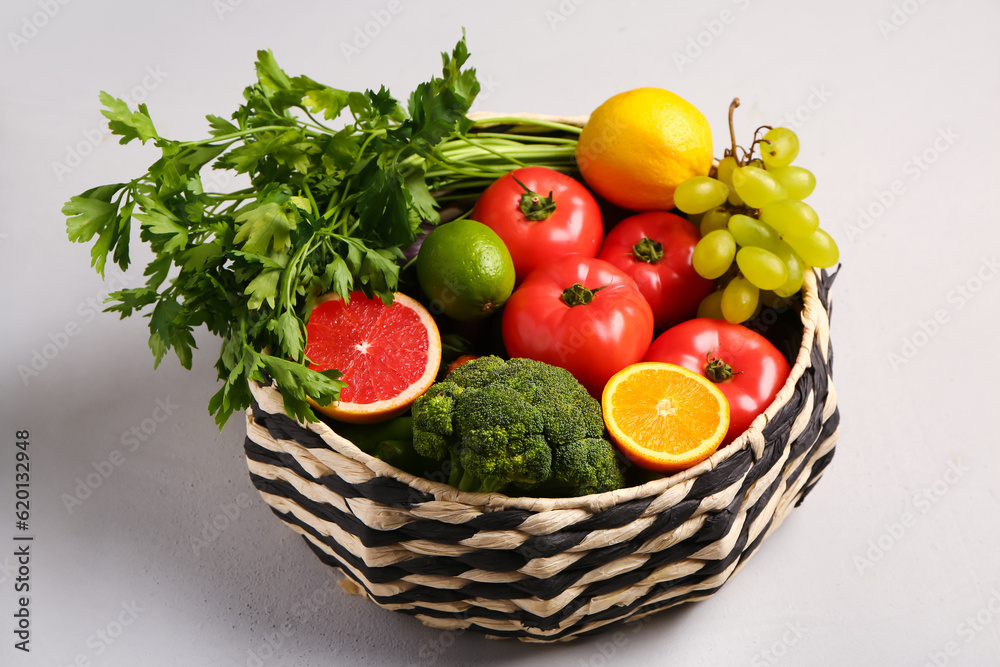 Wicker bowl with different fresh fruits and vegetables on white background