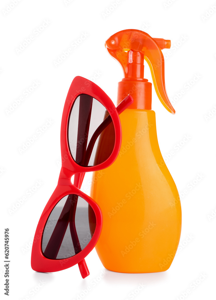 Stylish sunglasses with bottle of sunscreen cream isolated on white background