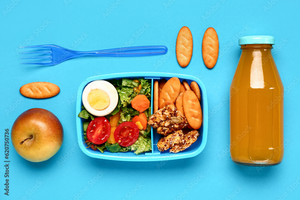 Bottle of juice and lunchbox with tasty food on blue background