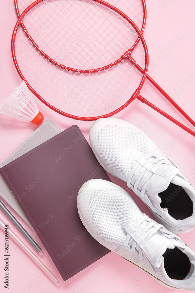 Sneakers with badminton shuttlecock, rackets and stationery on pink background