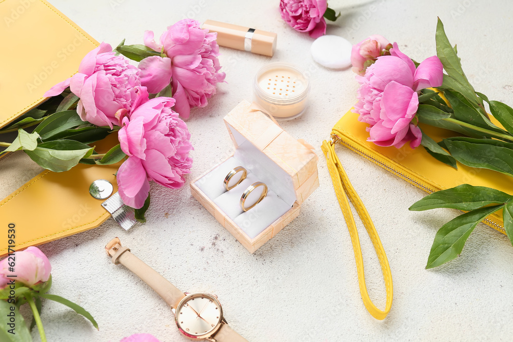 Composition with wedding rings, female accessories, cosmetics and beautiful peony flowers on light b