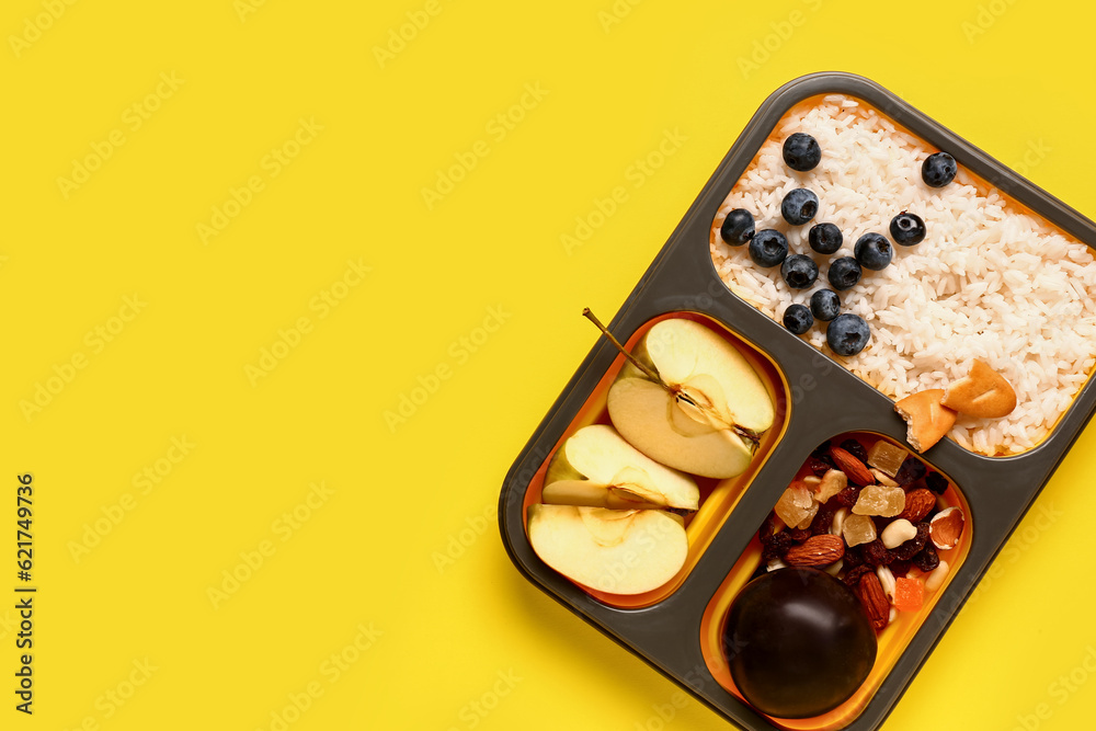 Lunchbox with tasty food on yellow background
