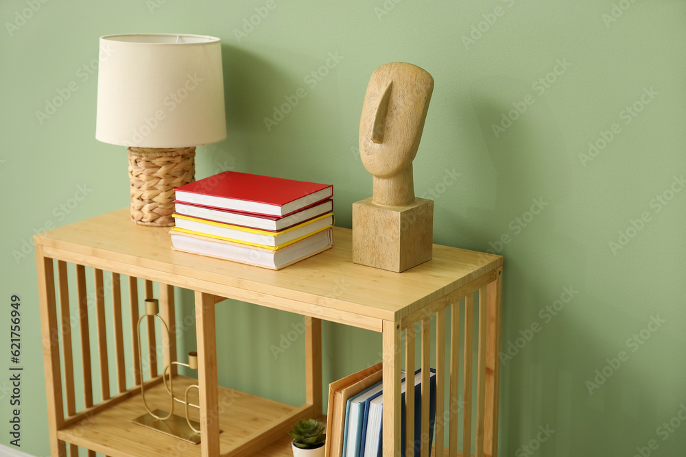 Shelving unit with books and lamp near green wall in room, closeup