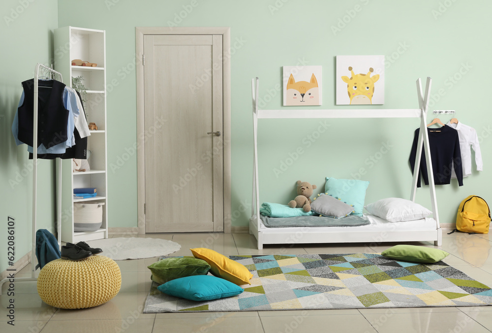 Stylish interior of childrens room with comfortable bed and school uniform