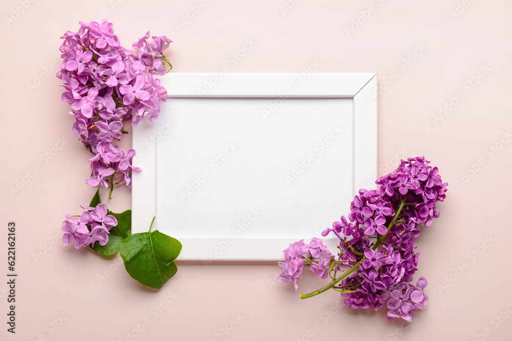 Composition with beautiful lilac flowers and blank frame on beige background