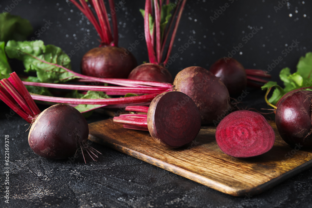 Wooden board with fresh beets on table