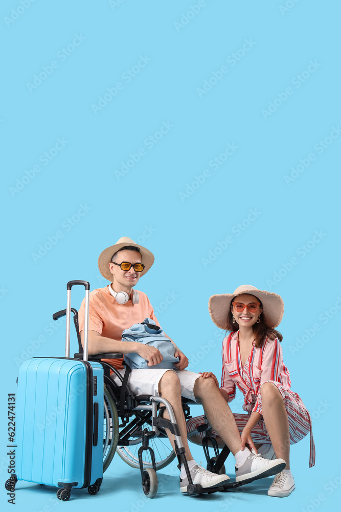 Young woman with her husband in wheelchair and bags on blue background