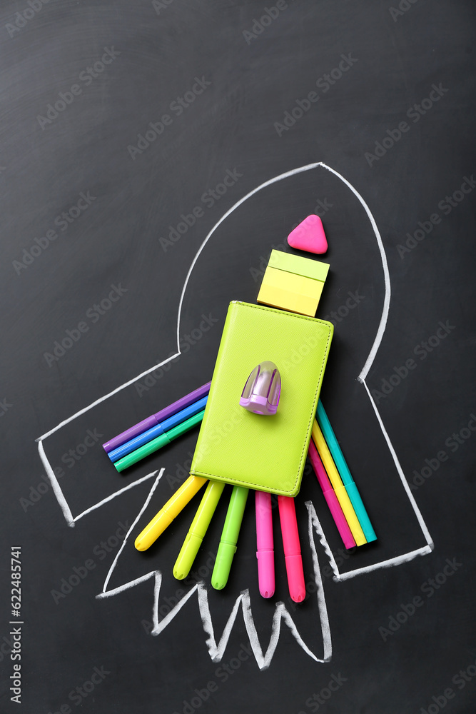 Drawn rocket with stationery on black background