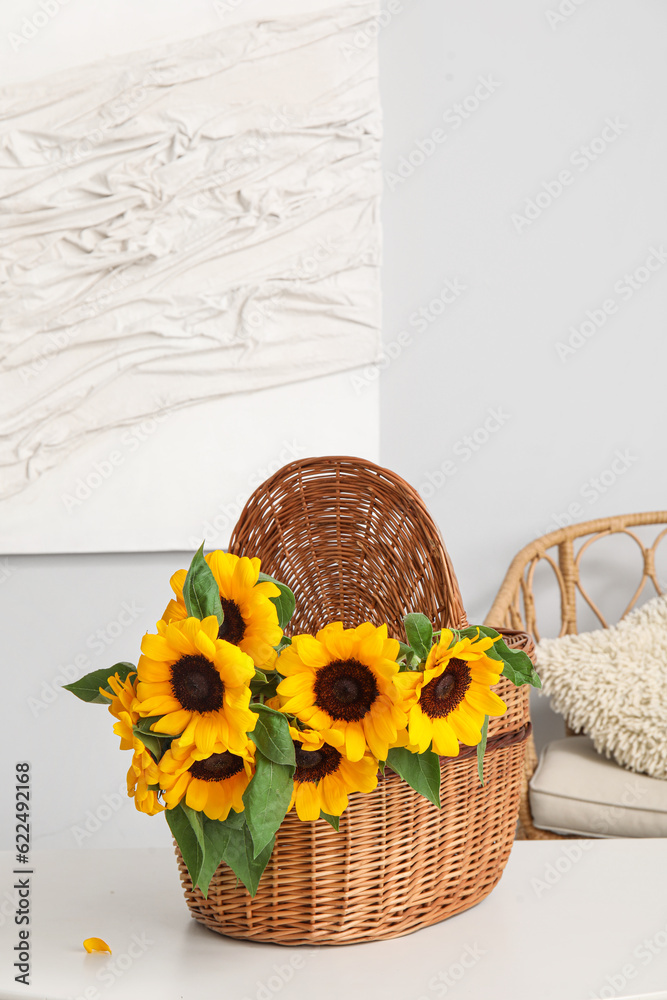 Wicker basket with sunflowers on table in dining room