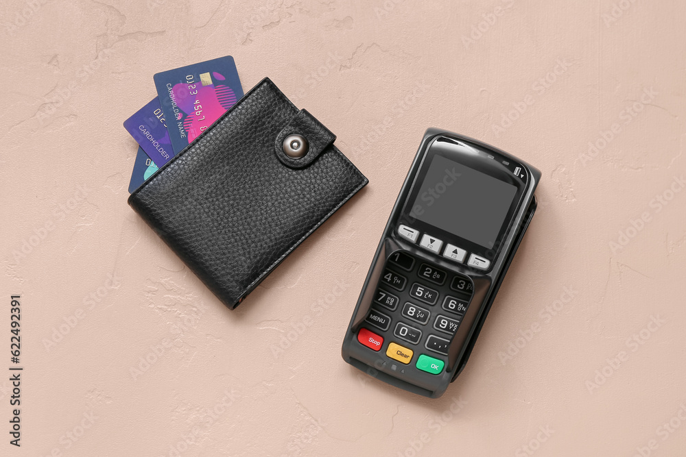Leather wallet with credit cards and payment terminal on brown background