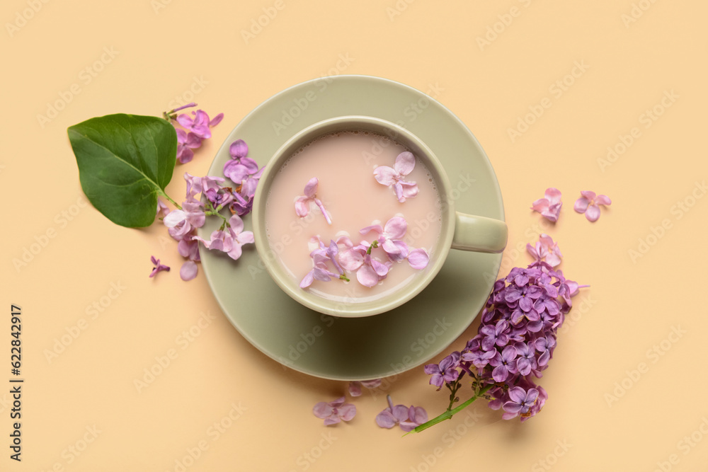 Cup of coffee and beautiful lilac flowers on beige background