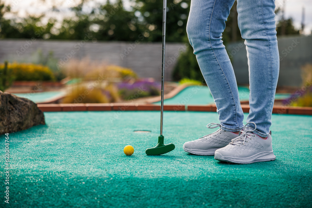 Woman playing mini golf game at outdoor course. Summer sport and leisure activity