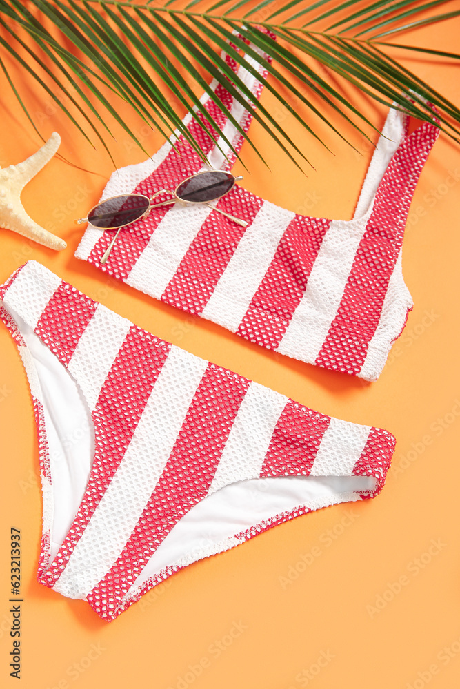 Striped swimsuit, sunglasses and palm leaf on color background, closeup