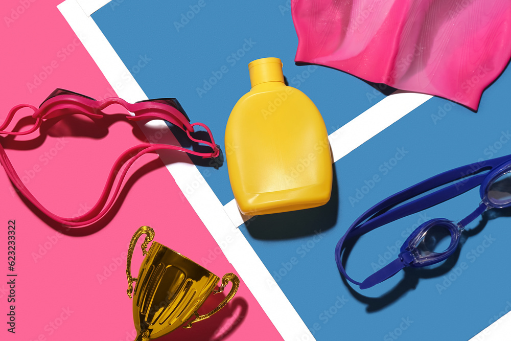 Composition with bottle of sunscreen cream, gold cup, goggles and swimming cap on color background