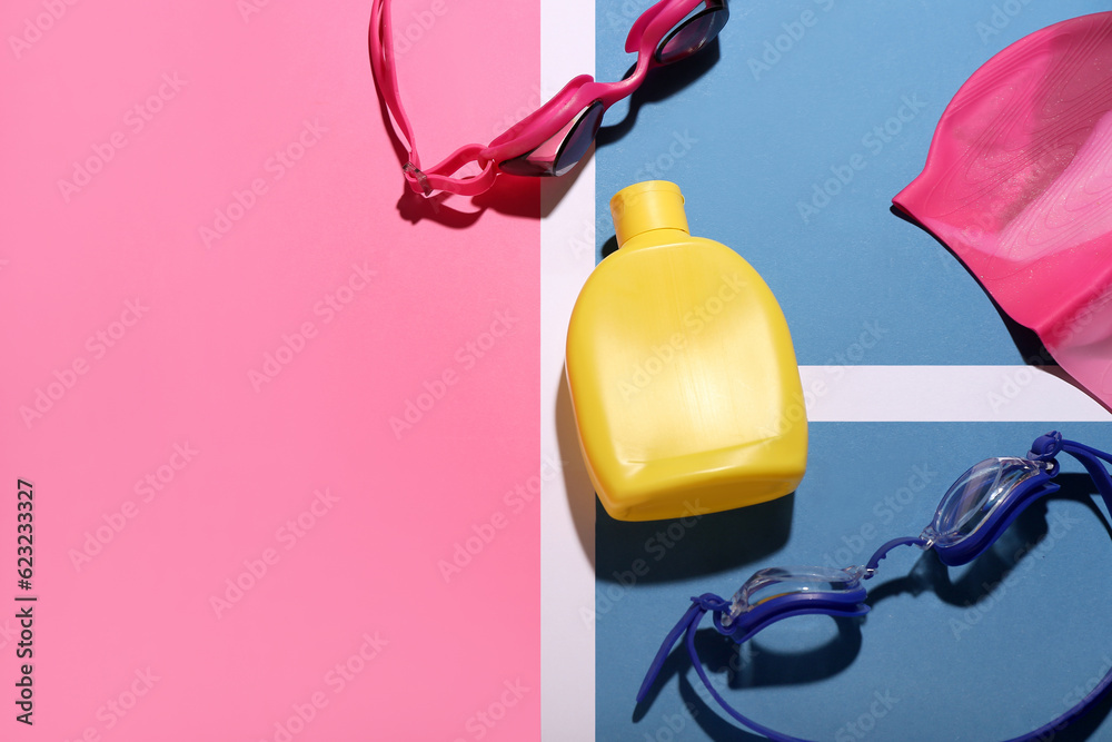 Bottle of sunscreen cream, goggles and swimming cap on color background