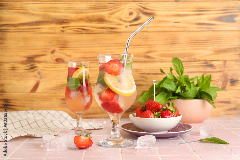 Glasses of fresh lemonade with strawberry and lemon on pink tile table