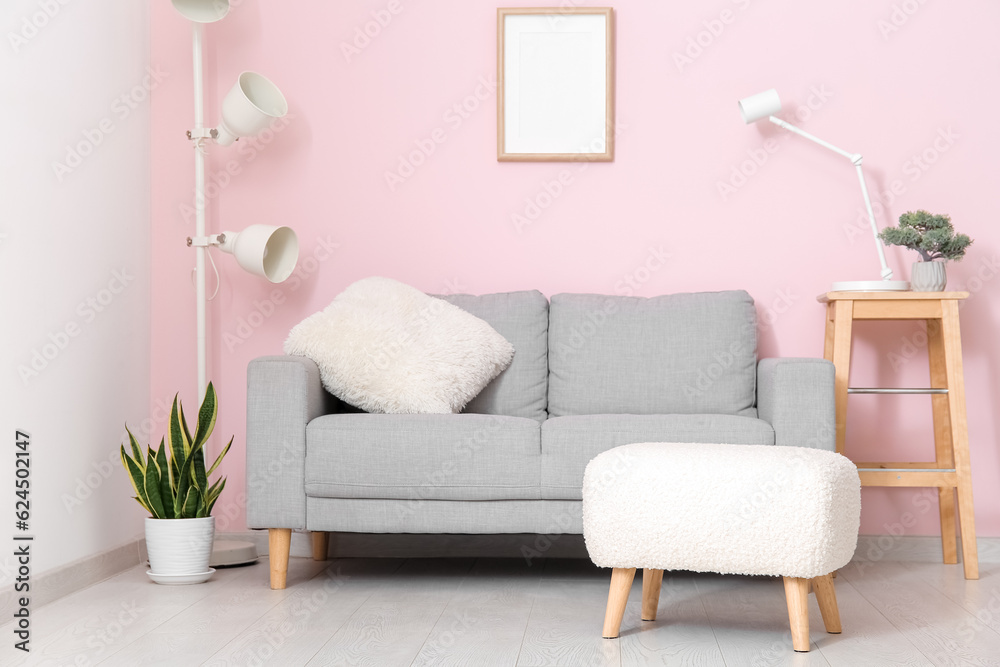 Interior of living room with sofa and ottoman near pink wall