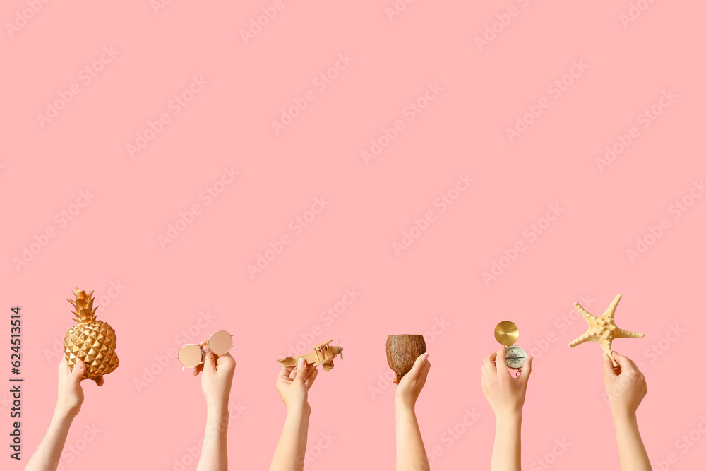 Many hands with compass, coconut and beach accessories on pink background