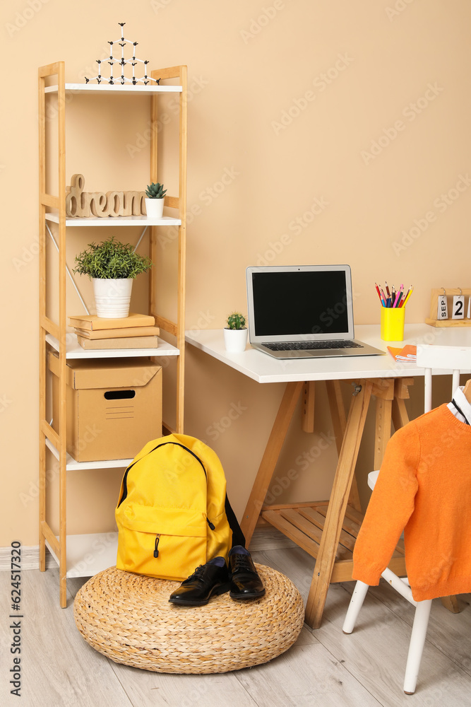 Stylish interior of childrens room with modern laptop and school uniform