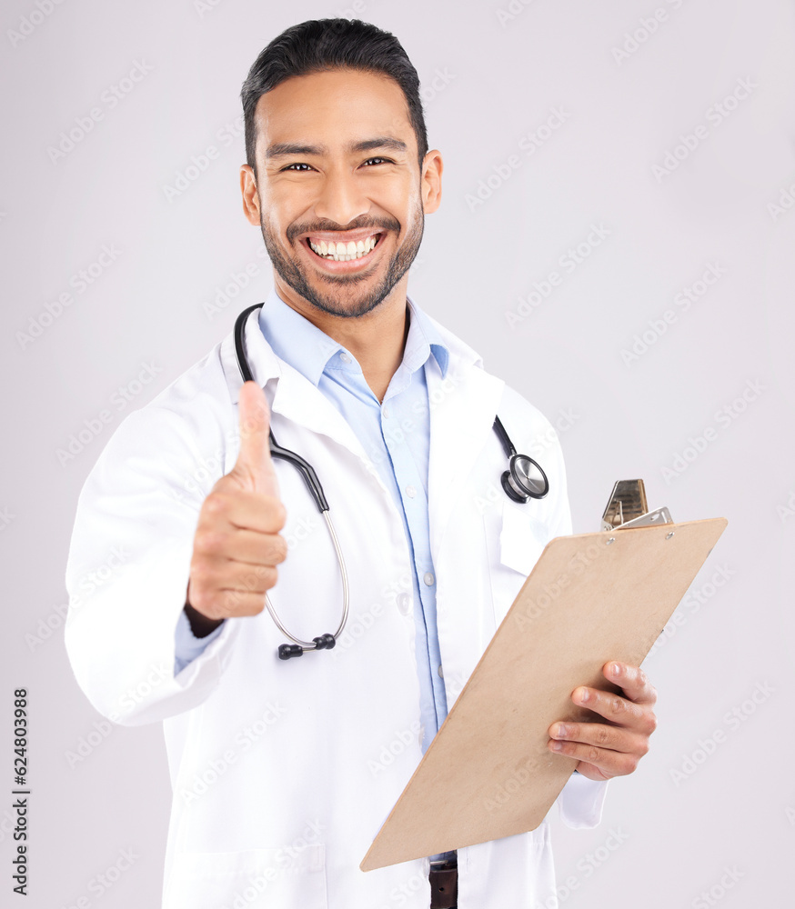 Happy asian man, doctor and portrait with thumbs up for healthcare approval against a grey studio ba