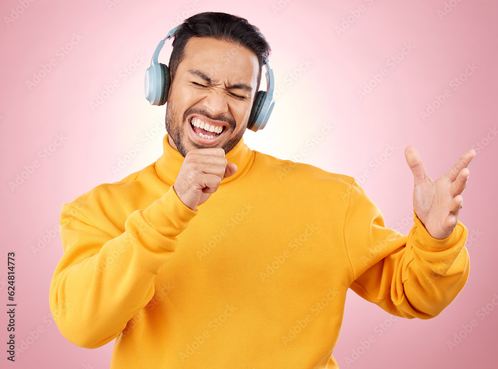 Asian man, headphones and listening to music while singing for karaoke against a pink studio backgro