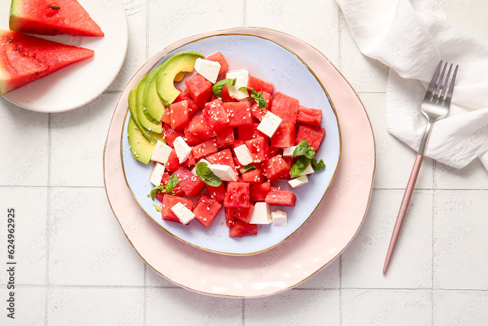 Plate of tasty watermelon salad on white tile background