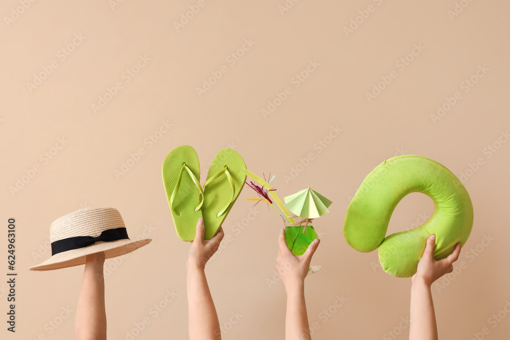 Female hands with beach accessories and cocktail on beige background