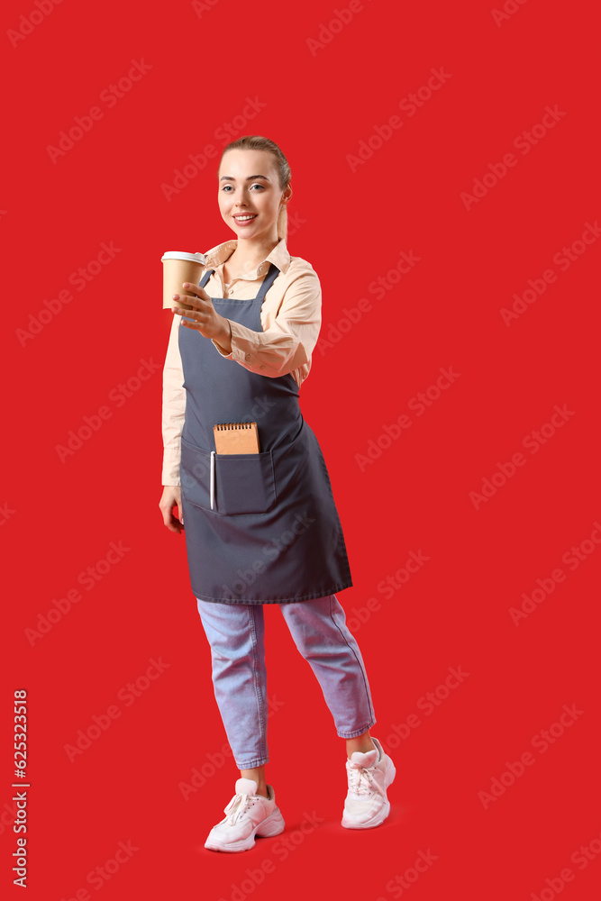 Young barista with cup of coffee on red background
