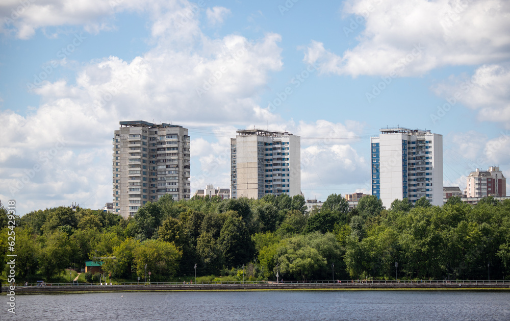 Multi-storey buildings in the green zone of the park against the sky.