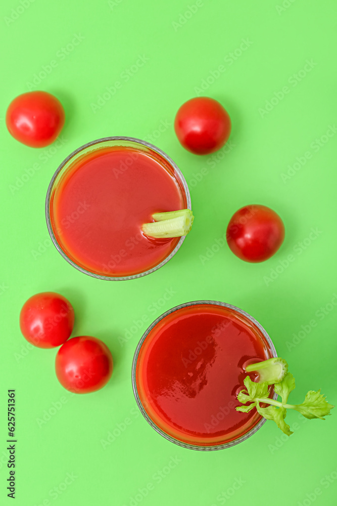 Glasses of tasty tomato juice on green background