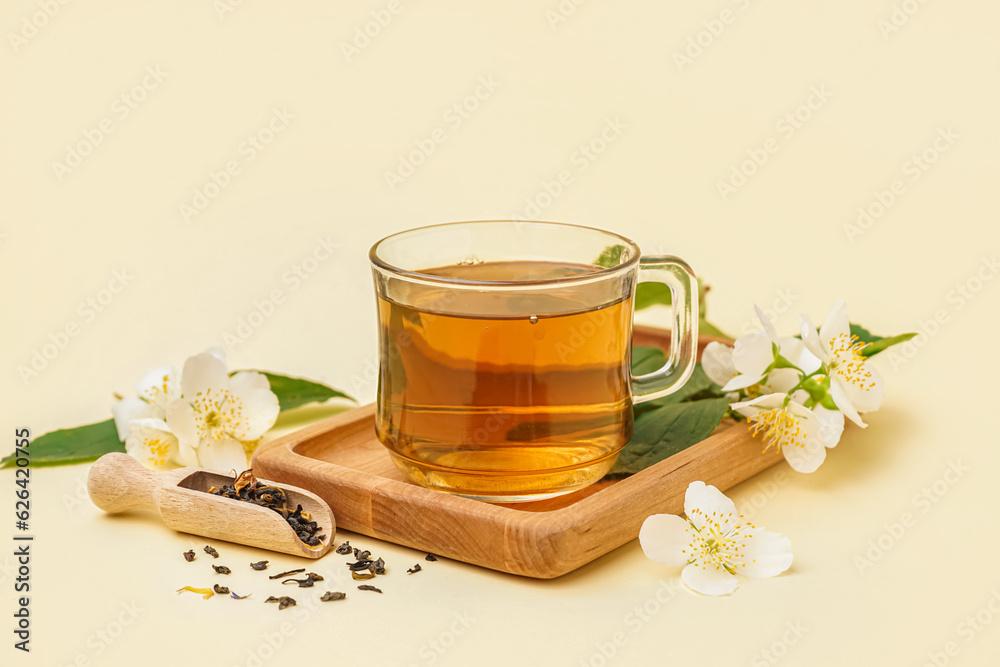 Cup of aromatic tea, dried leaves and beautiful jasmine flowers on color background