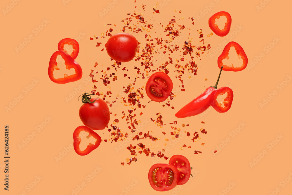 Flying vegetables and chili flakes on color background