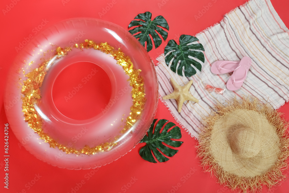 Inflatable ring with beach accessories on red background