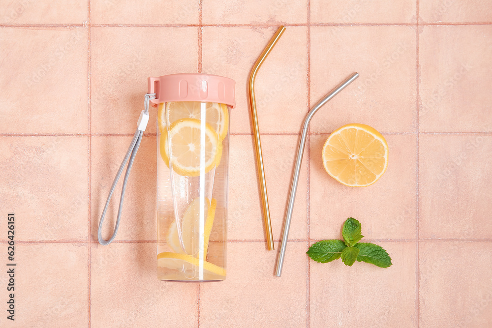 Sports bottle of infused water with lemon and mint on pink tile background
