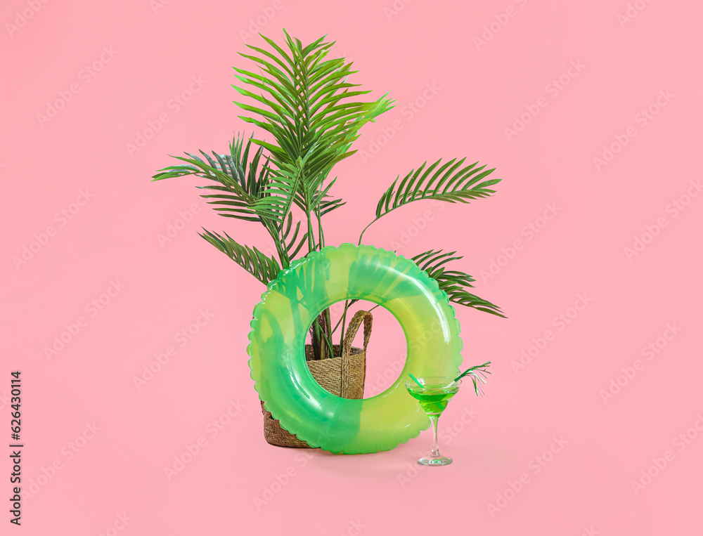 Swim ring with palm and cocktail on pink background