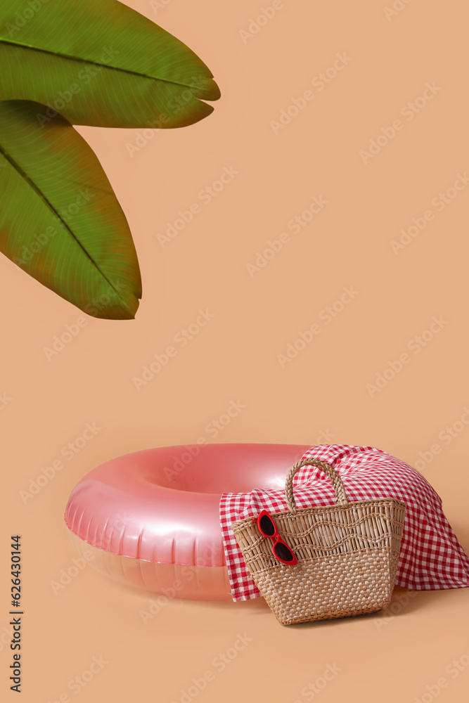 Swim ring with beach accessories and palm leaves on beige background