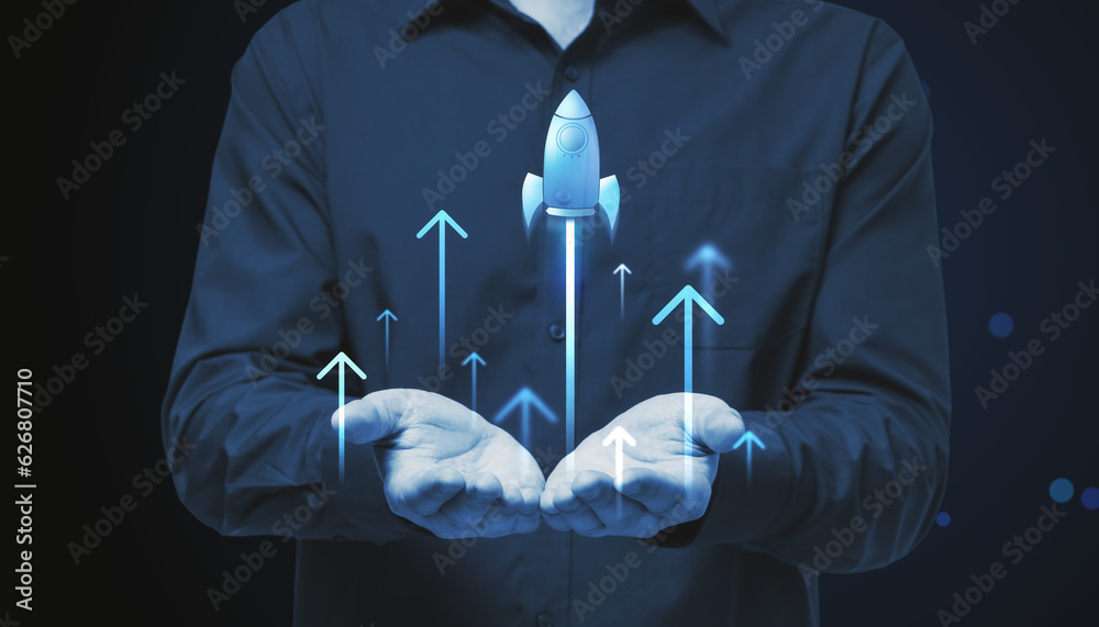 Close up of businessman hands holding glowing flying blue rocket on blue background. Start up and la