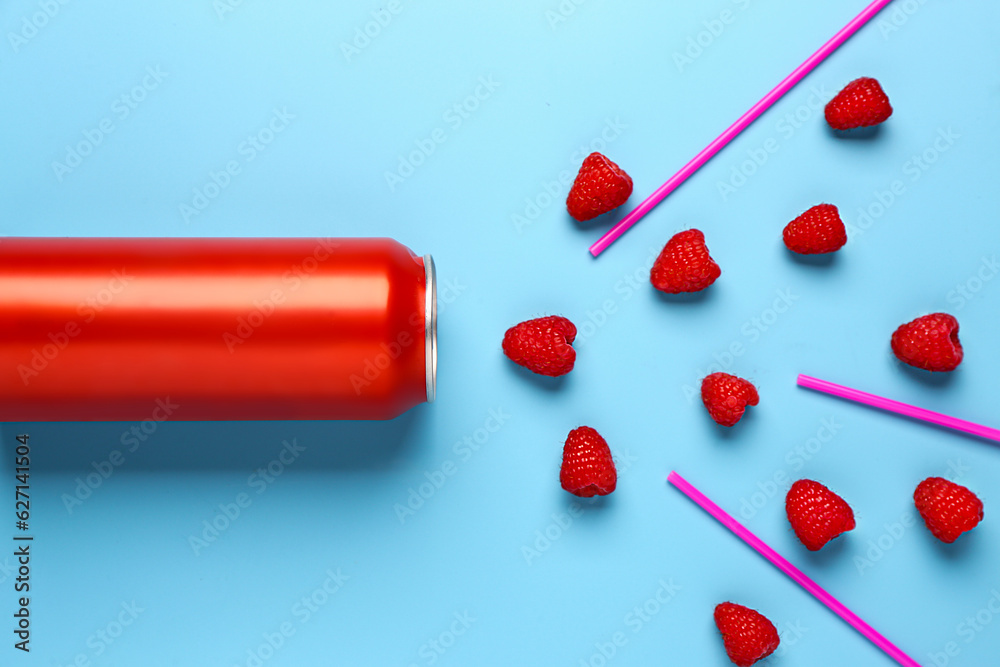 Composition with can of fresh soda and raspberry on blue background
