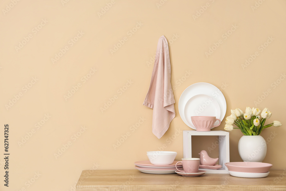 Set of clean dishes and vase with tulip flowers on wooden countertop