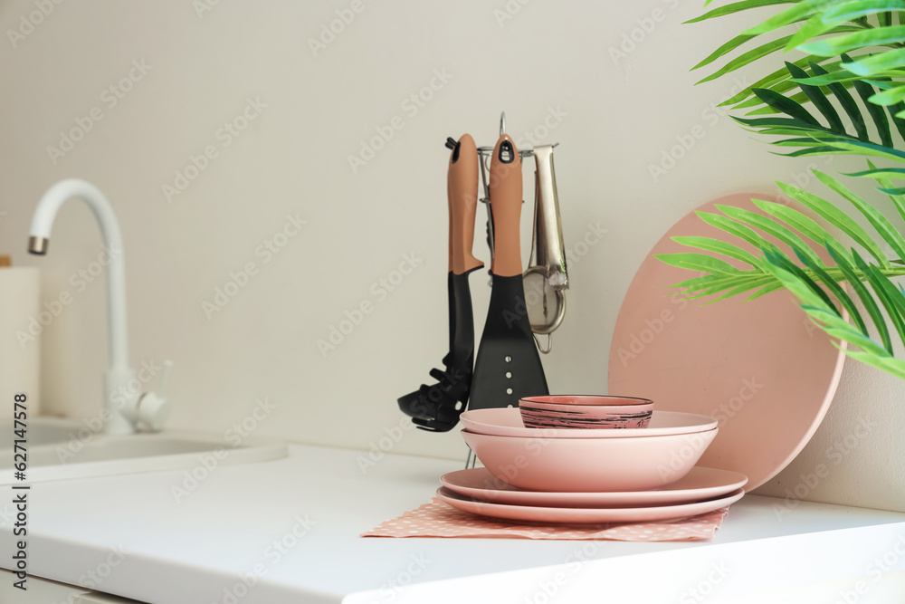 Clean dishes and kitchen utensils on white counter, closeup