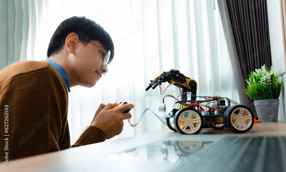 Asian teenager constructing robot arm project in house. technology of robotics programing and STEM e